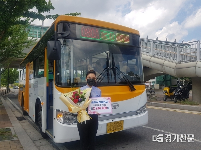 파주 마을버스 최우수 기사로 선정된 박경민씨가 격려금과 꽃다발을 들고 자신이 운행하는 080A번 버스 앞에서 포즈를 취하고 있다. (사진=파주시 제공)