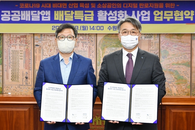 박사승 수원시 경제정책국장(왼쪽)과 이석훈 경기도주식회사 대표이사가 19일 수원시청 상황실에서 '경기도 공공배달앱 배달특급 활성화 사업 운영대행 업무협약'을 체결한 뒤 기념촬영을 하고 있다. (사진 = 경기도주식회사 제공)