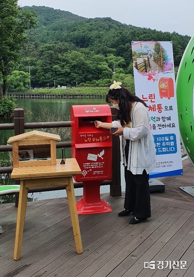 최근 인기를 끌고 있는 고모호수공원에 설치된 느린 유체통. 한 관광객이 엽서를 넣고 있다. (사진=포천시 제공)