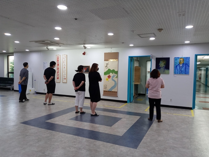군포시청 2층 대회의실 입구에 전시돼있는 군포지역예술인들의 작품을 시민들이 감상하고 있다. (사진=군포시 제공)