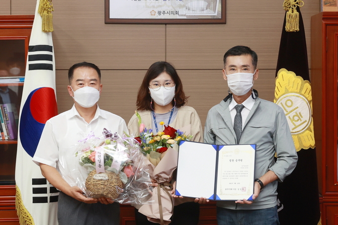 광주시의회가 시 감사담당관실 소속 김민경 주무관(사진 가운데)을 8월 칭찬공무원으로 선정했다. 김 주무관을 추천한 박현철 의원(왼쪽)과 임일혁 의장이 함께 증서와 꽃다발을 들어보이고 있다. (사진=광주시의회 제공)