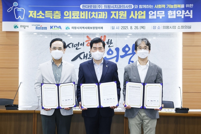 김상돈 의왕시장(사진 가운데)과 이용배 현대로템 대표이사, 엄태호 의왕시치과의사회장이 26일 의왕시청 소회의실에서 열린 '저소득층 의료비(치과) 업무협약식'에서 각자 서명한 협약서를 들어보이고 있다. (사진=의왕시 제공)