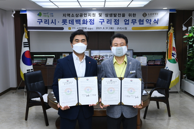 안승남 구리시장(사진 오른쪽)과 롯데백화점 조시훈 구리점장이 업무협약을 맺고 각자 서명한 협약서를 들어보이고 있다. (사진=구리시 제공)