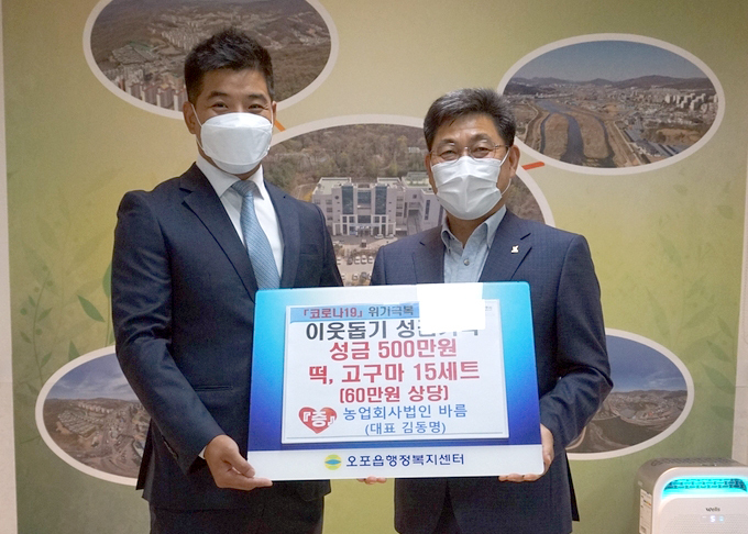 농업회사법인 바름 김동명 대표가 권용석 오포읍장에게 성금 500만원과 떡, 고구마 15세트(60만원 상당)를 기탁하고 있다.(사진=광주시제공)
