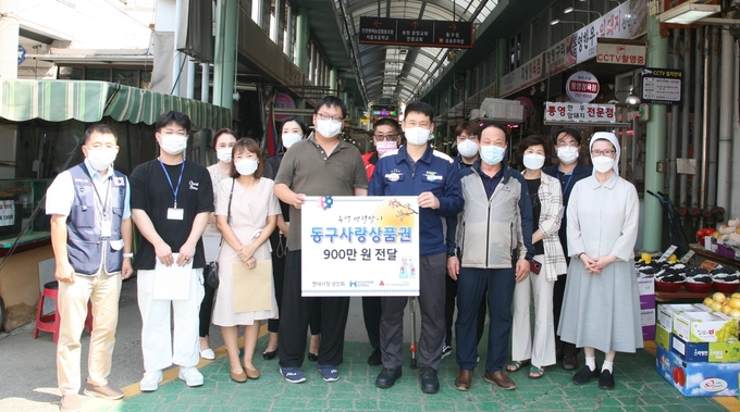 현대제철 관계자가 전통시장을 방문, 동구사랑상품권 전달식을 갖고 상인들과 함께 사진촬영을 하고 있다. ( 사진 = 현대제철 제공 )
