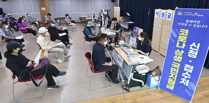 코로나 상생 국민지원금 오프라인 신청 첫 날인 13일 수원시 팔달구 행궁동 행정복지센터에 마련된 접수처가 신청자들로 붐비고 있다. (사진=경기신문 황준선 기자)