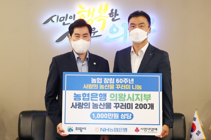 김상돈 시장(사진 왼쪽)이 한명호 NH농협은행 의왕시지부장으로부터 사랑의 농산물 꾸러미 200개(1000만 원 상당)을 전달받고 있다. (사진=의왕시 제공)