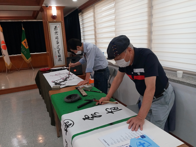 미술분과 김원술 작가(사진 왼쪽)가 매화를 치고 노천수 작가가 가훈을 써내려 가고 있다. (사진=김대성 기자) 