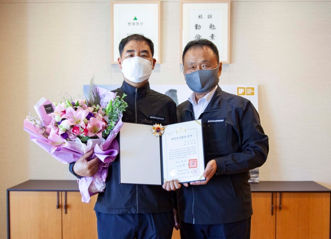 대한민국 명장 김주호 기술부장(왼쪽)을 현대두산인프라코어 손동연 사장이 격려하고 있다. ( 사진 = 현대두산인프라코어 제공 )