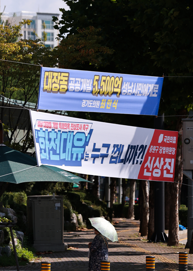  24일 경기도 성남시청 인근 교차로에 성남 대장동 개발 사업과 관련해 더불어민주당 소속 경기도의회 의원과 국민의힘 지역 당협위원장 이름으로 상반된 의미를 담은 현수막이 나란히 걸려 있다. (사진=연합뉴스)