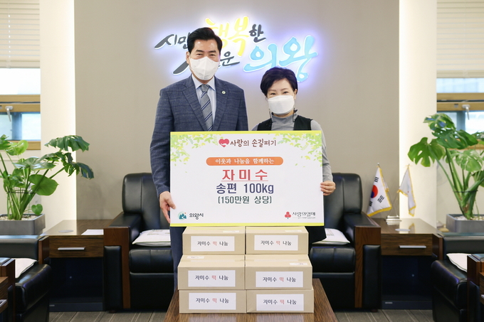 김상돈 의왕시장(사진 왼쪽)이 자미수 신봉금 대표로부터 송편 100㎏을 전달받으며 기념촬영을 하고 있다. (사진=의왕시 제공)