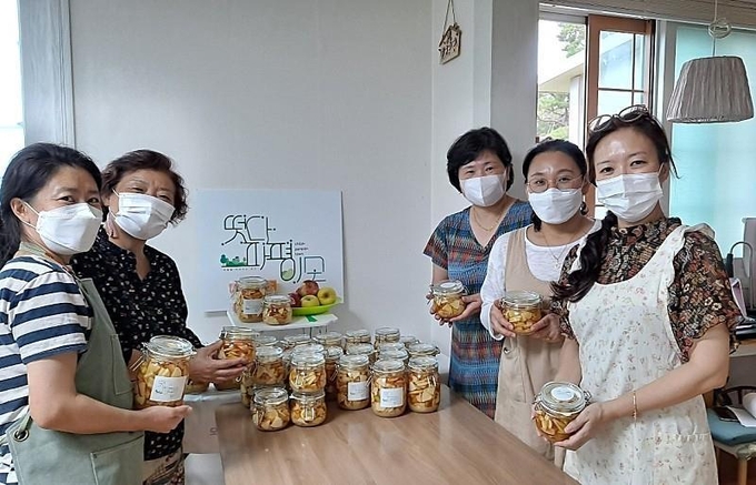 파평면 마을공동체 '떳다~파평이모' 회원들이 사과청을 들어보이고 있다. (사진=파주시 제공)