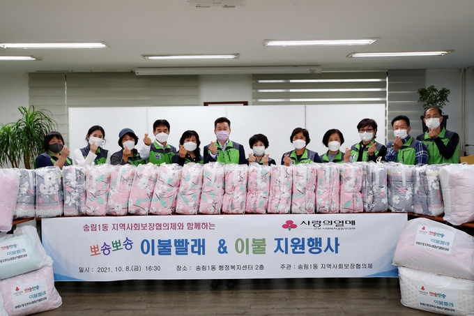 깨끗하게 세탁을 마친 이불과 새 이불을 직접 배달하고 있는 허인환 구청장과 송림1동 지역사회보장협의체 위원들. ( 사진 = 동구 제공 )
