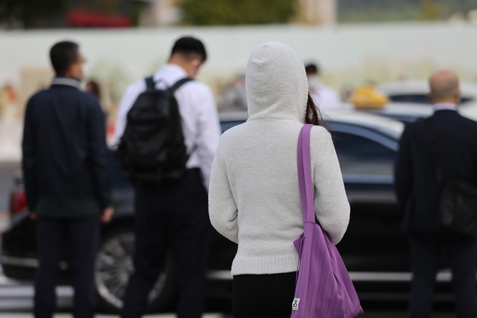  쌀쌀한 날씨를 보인 12일 오전 서울 종로구 광화문네거리에서 후드가디건 모자를 눌러쓴 한 시민이 발걸음을 옮기고 있다. (사진=연합뉴스)