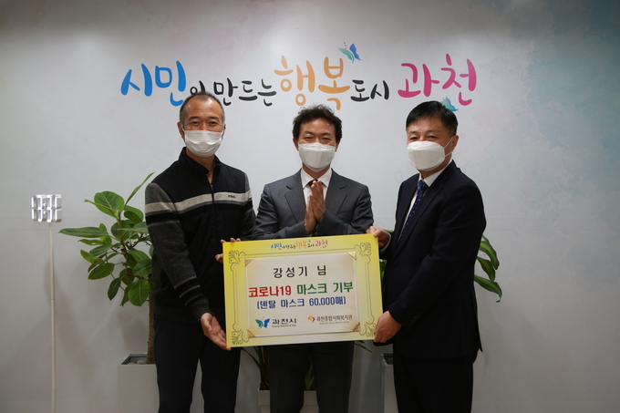 강성기(왼쪽 첫번째) 씨가 지난 22일 코로나로 지쳐있는 과천시민들에게 전달해 달라며 덴탈마스크 6만장을 김종천 과천시장에게 기탁하고 있다.(사진= 과천시 제공)