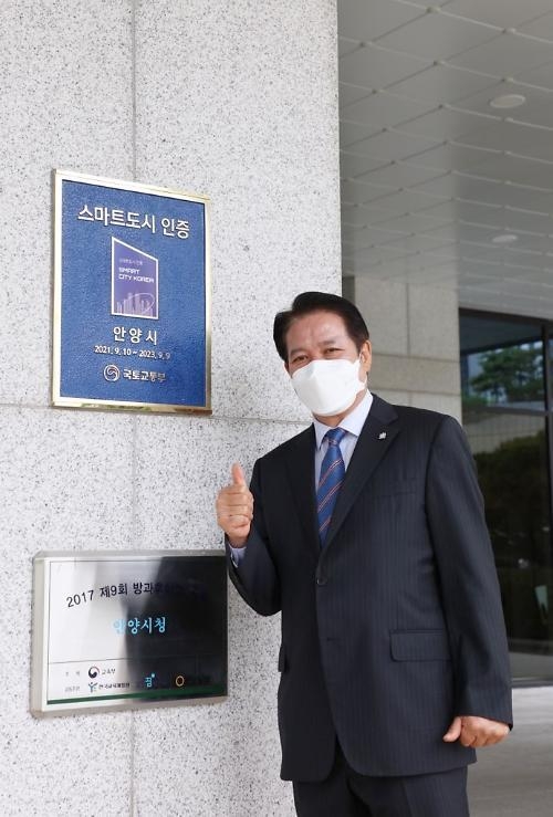 최대호 안양시장이 국토교통부로부터 받은 스마트도시 인증패 앞에서 포즈를 취하고 있다. (사진=안양시 제공)