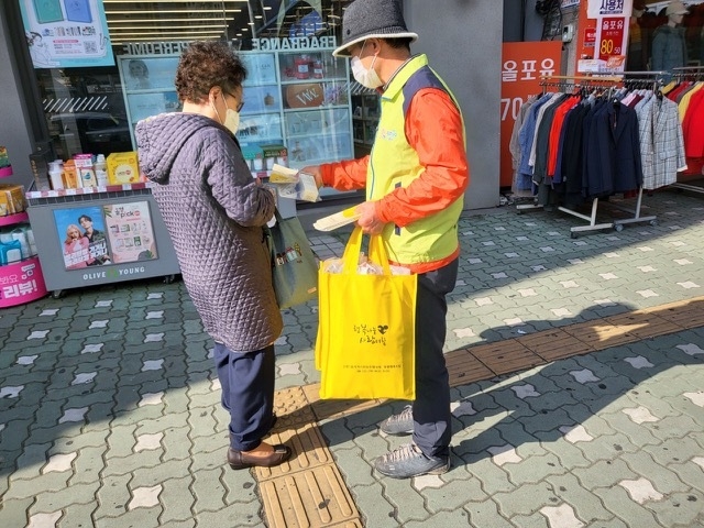 군포시 산본1동 지역사회보장협의체 위원이 한 시민에게 복지사각지대 발굴 캠페인 홍보물을 전달하고 있다. (사진=산본1동 제공)