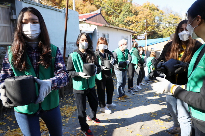 봉사활동에 나선 한국조지메이슨대 교직원과 학생들이 연탄을 나르고 있다. ( 사진 = 한국조지메이슨대 제공 )