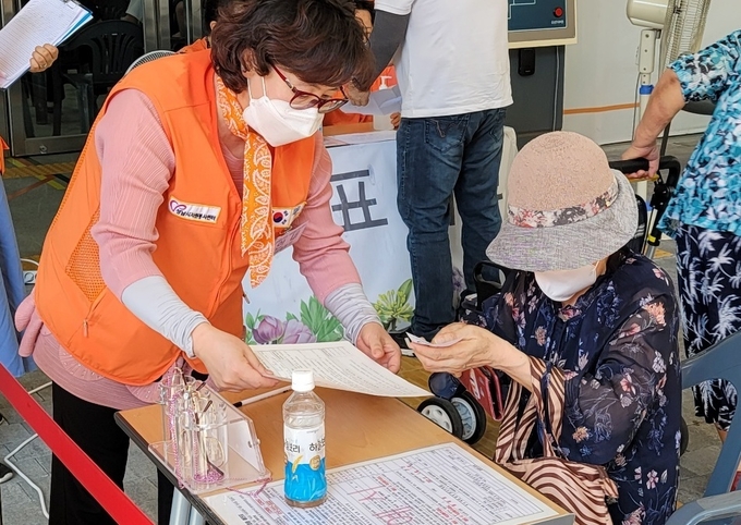 자원봉사자가 어르신 예진표 작성에 도움을 드리고 있다. (사진=성남시자원봉사센터 제공)