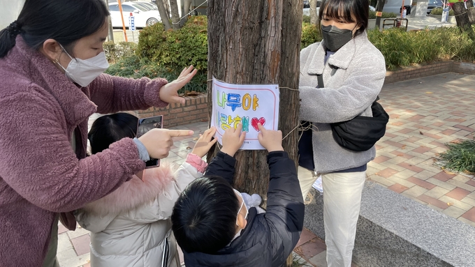 계산1동 어린이들이 '나무야 사랑해'라는 문구를 만들어 가로수에 둘러주고 있다. ( 사진 = 계양구 제공 ) 