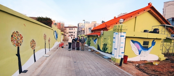 김포시 통진읍 청사초롱길 골목 담벼락에 그려낸 벽화를 감상하고 있는 젊은 청년들이 얘기를 나누고 있다. (사진=김포시 통진읍 제공)