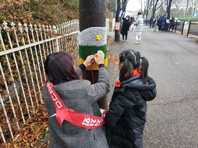 파주시 금촌2동 공릉천변 가로수에 시민 자신이 직접 제작한 겨울 옷을 입히고 있다. (사진=파주시 제공)