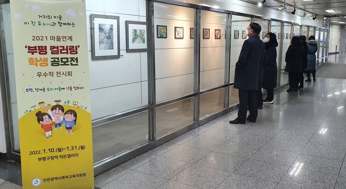 부평구청역 작은갤러리에 전시 중인 부평 컬러링 학생공모전 작품을 시민들이 둘러보고 있다. ( 사진 = 인천교육청 제공 )