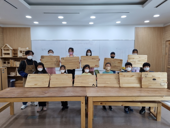 겨울방학 초등 긴급돌봄 프로그램이 개강해 학생들이 수업 결과물과 함께 기념촬영을 하고 있다. (사진=성남시청소년재단 제공)