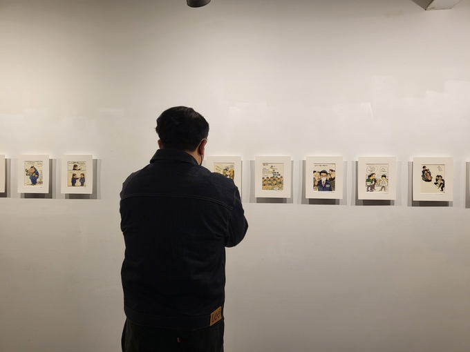 박재동 화백 '한판 붙자' 전시를 감상 중인 관람객의 모습. (사진= 정경아 기자)