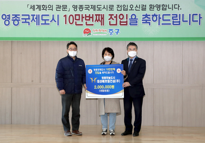 홍인성 구청장(온른쪽)이 영종국제도시 인구 10만 명 돌파를 기념해 10만 번째 전입자에게 축하물품을 전달하고 있다. ( 사진 = 중구 제공 )
