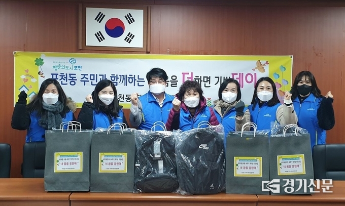 포천동지역사회보장협의체 회원들이 어린이들에게 나누어 줄 가방 앞에서 기념촬영하고 있다. (사진=포천시 제공)