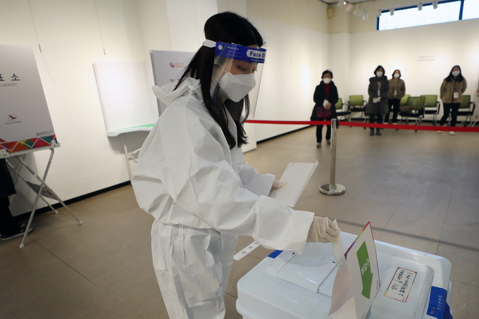 제20대 대통령선거 사전 투표 이틀째인 5일 오후 광주 서구 학생교육문화회관에 마련된 상무1동 사전투표소에서 확진·격리자들이 투표한 투표용지를 방역복을 입은 관계자가 전달받아 투표함에 넣고 있다. (사진=연합뉴스 제공)