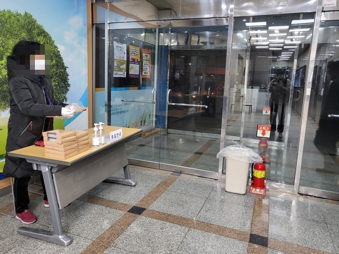투표소 1층 로비에서 투표사무원이 투표를 하러 온 사람들에게 비닐장갑을 나눠주고 있다. (사진= 이명호 기자)