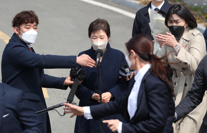  24일 오후 박근혜 전 대통령이 대구 달성군 사전에 도착해 대국민 담화문을 밝히던 중 갑자기 소주병이 날아들자 경호원들이 박 전 대통령을 에워싸고 있다. (사진=연합뉴스 제공)