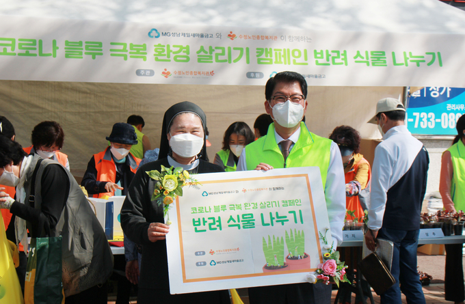 MG성남제일새마을금고 김중옥 이사장(사진 오른쪽)이 반려식물 나누기 행사에 참여해 기념촬영을 하고 있다. (사진=수정노인종합복지관 제공)