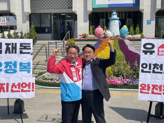 유정복 예비후보와 심재돈 당협위원장이 어깨동무를 한 채 손을 들어올리고 있다. ( 사진 = 조경욱 기자 )