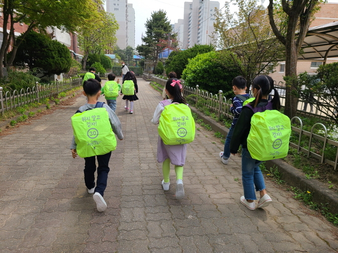 구리시가 제작해 초등학교 1~2학년생들에게 전달한 ‘가방 안전 덮개’를 사용하고 있는 어린이들.(사진=구리시 제공)