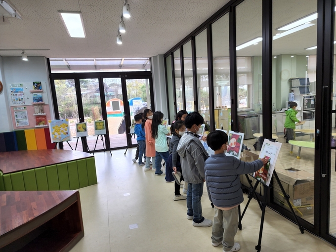 오산초등학교 학생들이 도서관에 전시된 그림책 원화를 감상하고 있다. (사진=오산초등학교 제공)