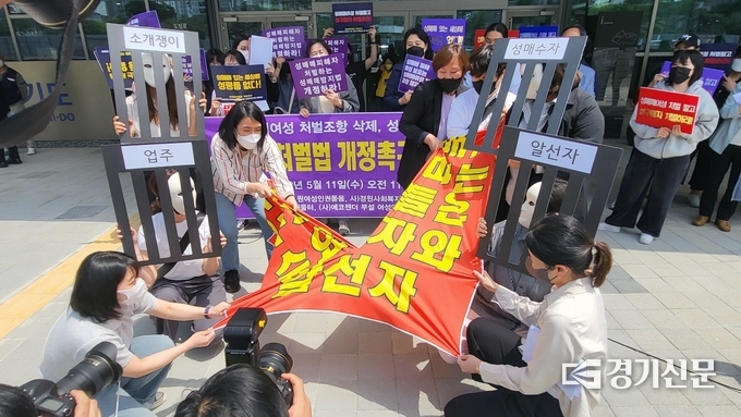 경기지역 성매매처벌법개정연대는 11일 경기도의회 앞에서 진행한 기자회견 끝에는 '성매매, 사고 파는 주체들은 수요자와 알선자'가 적힌 현수막을 찢는 퍼포먼스를 펼쳤다. (사진=김한별 기자)
