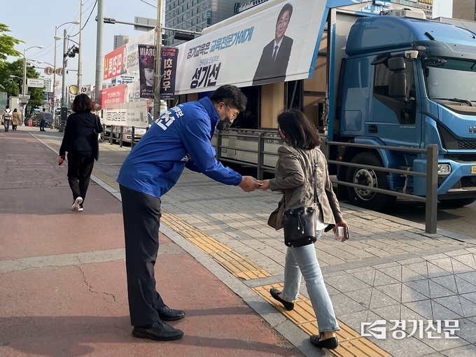 성기선 경기도교육감 후보가 수원역에서 출근하는 시민에게 인사를 하고 있다. (사진=강현수 기자)