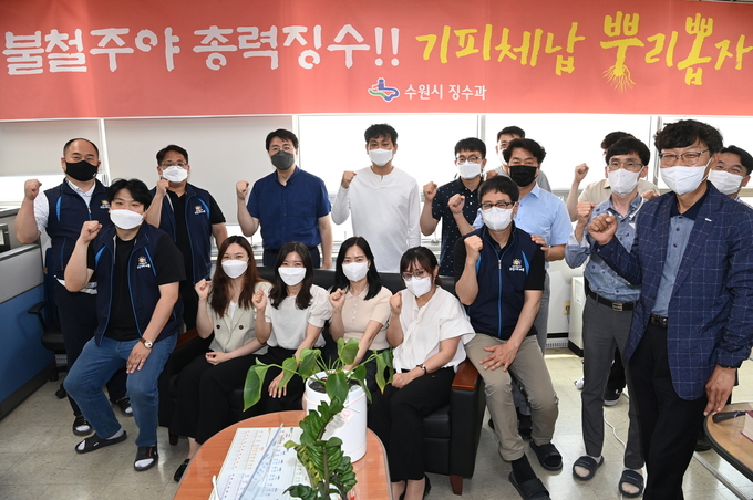 지방세 체납액 징수 업무를 담당하고 있는 수원시 징수과 직원들이 ‘기피체납 뿌리뽑자’는 현수막을 배경으로 파이팅을 외치고 있다. (사진=수원시 제공)