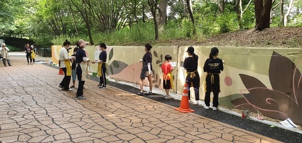 직장인, 대학생 등으로 구성된 봉사단체 네오맨 관계자들이 월미공원 둘레길 옹벽에 벽화를 그리고 있다. ( 사진 = 인천시 제공 )