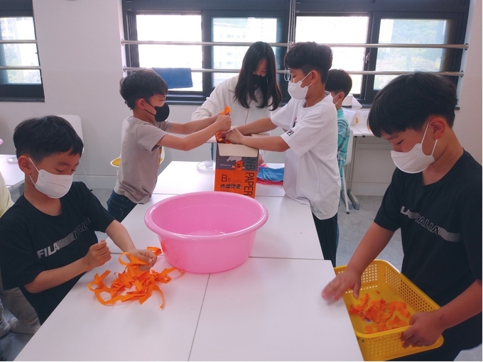 더숲도서관에서 '폐지로 수제 종이 만들기' 활동중인 백운초등학교 학생들. (사진=백운호수초등학교 제공)