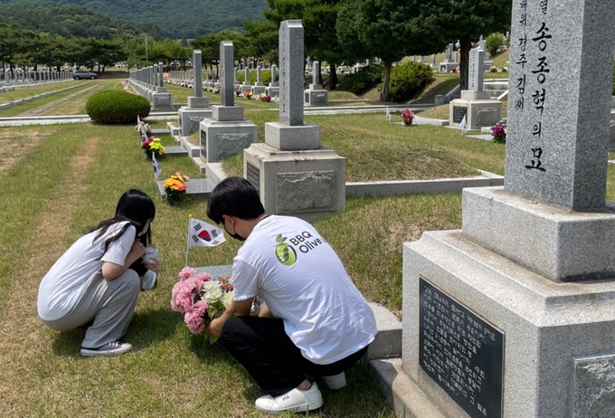 BBQ 대학생 봉사단 올리버스(Olive Us)가 묘역 내 시든 꽃을 교체하고 있다. (사진=제너시스BBQ 제공)