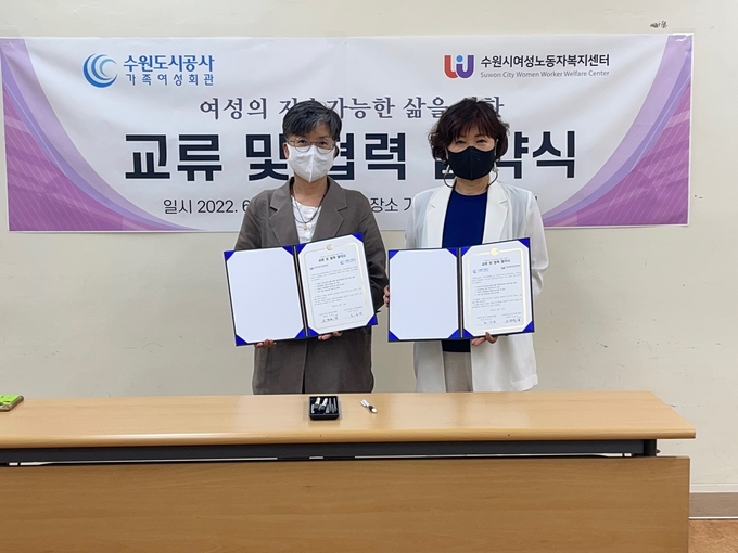 가족여성회관 권금상 관장(오른쪽)과 수원시여성노동자복지센터 조영숙 센터장이 업무협약을 맺고 기념촬영을 하고 있다. (사진=수원도시공사 제공)