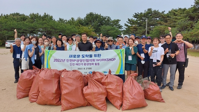 인천지식재산센터 직원들과 인천IP경영인협의회원들이 21일 실미도 해안가를 청소하고 기념촬영을 하고 있다. ( 사진 = 인천상공회의소 제공 )