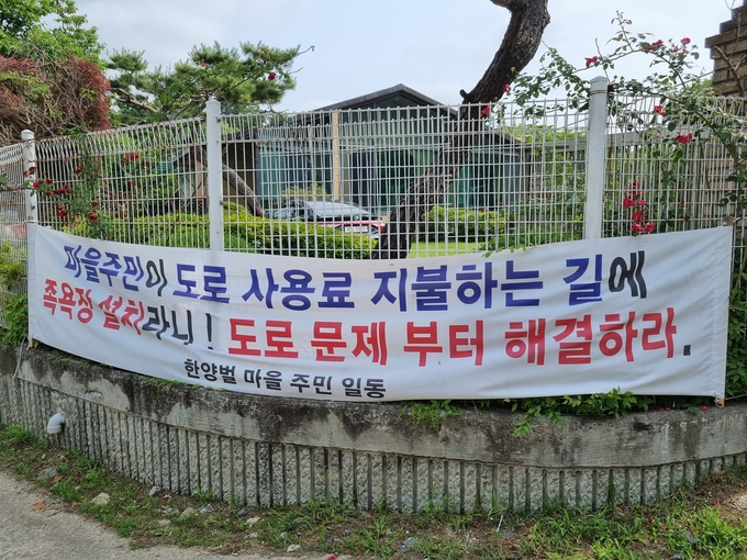 한양벌 마을 주민들이 도로 문제 해결을 촉구하는 현수막 (사진=이화우 기자)