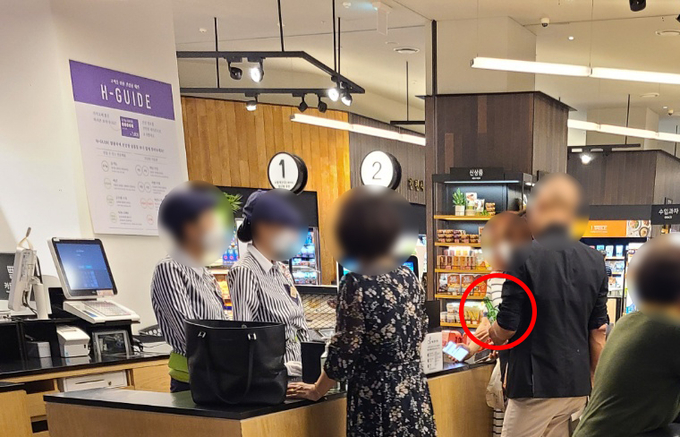 현대백화점 판교점에서 취객이 다른 이용객에게 소주 가격 계산을 요구하고 있다. 이를 제지하는 현대백화점 직원은 없었다. (사진=제보자 제공)