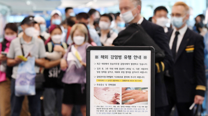인천국제공항 제1터미널 입국장에 해외 입국자들이 검역을 받기 위해 대기하고 있다. 승객들 앞에는 원숭이두창 관련 안내문이 세워져 있다. (사진=연합뉴스 제공)