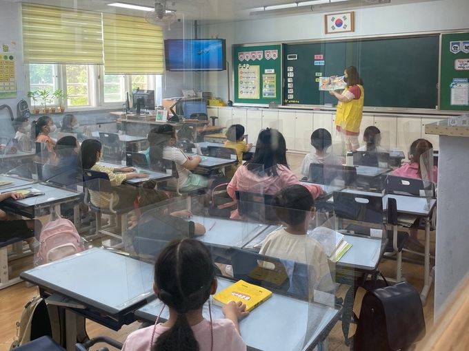  평택덕동초등학교 학부모 동아리 ‘책꿈맘’ 회원이 학생들에게 그림책을 읽어주고 있다. (사진=평택덕동초등학교 제공)